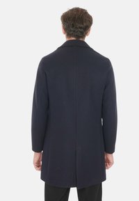 Cappotto di lana blu navy con taglio dritto, ampi rever e maniche lunghe, caratterizzato da una cucitura centrale sul retro e da una texturesmooth.