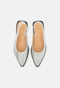 Ezüst színű, hegyes orrú slingback cipők sima fémes felülettel, bézs bélés és fekete gumitalp kontrasztként. Látható fémrészlet nélkül készült.