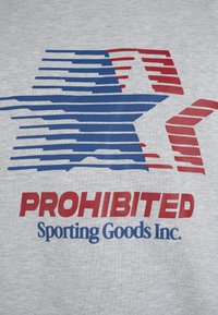 Étoile stylisée bleue et rouge avec des lignes fragmentées au-dessus du texte en rouge gras « PROHIBITED » et bleu « Sporting Goods Inc. » sur fond de tissu gris.
