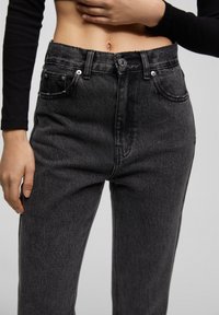 Höga svarta denimjeans med en lätt tvättad finish, försedda med framfickor och knappstängning. Rakt ben och texturerad väv.