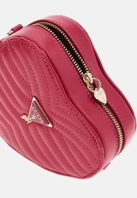 Ronde roze leren tas met doorgestikte textuur, gouden rits en hartvormige metalen details met het merklogo.