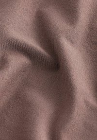 Hnědá látka s hladkým povrchem, s jemným strečovým efektem a drobnými tkanými detaily. Materiál působí lehkým a měkkým dojmem.