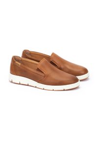 Zapatos marrones tipo slip-on hechos de cuero perforado, con una punta lisa y suela de goma blanca, que presentan un diseño minimalista y una marca sutil.