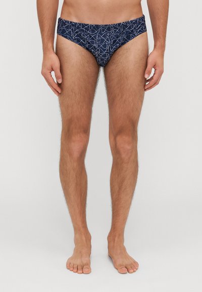Navy swim briefs featuring a white geometric pattern, elastic waistband, and a snug fit. Made from smooth fabric for comfort.