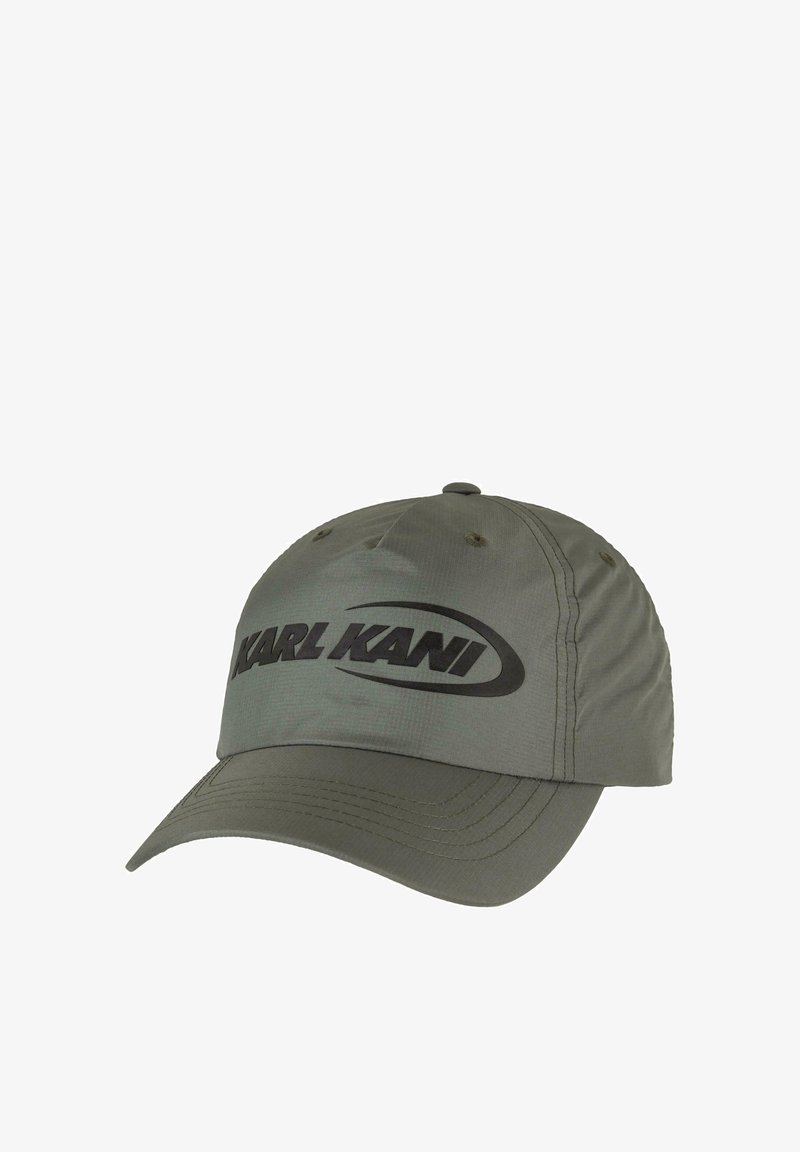 Olīvu zaļa beisbola cepure ar izliekto malu, ar lielu melnu logo priekšpusē un redzamām stīgām akcentiem uz viziera.
