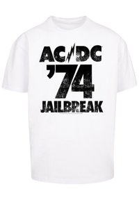 White cotton t-shirt featuring a bold black graphic print of "AC/DC '74 JAILBREAK," with a distressed texture and lightning bolt accent.