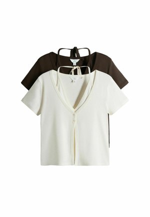 Dva krátká svetry na knoflíky v krémové a tmavě hnědé barvě, každý s výstřihem do V a knoflíky na přední straně, vrstvené na bílém pozadí.