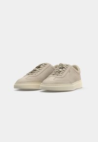 Pair of light beige suede sneakers with cream rubber soles and lace-up fronts against a plain white background.
