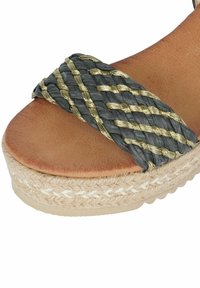 Sandali con cinturino intrecciato grigio e oro, dotati di una suola in piattaforma color tan, con una trama intrecciata e un fondo simile al juta per un tocco di dettaglio in più.