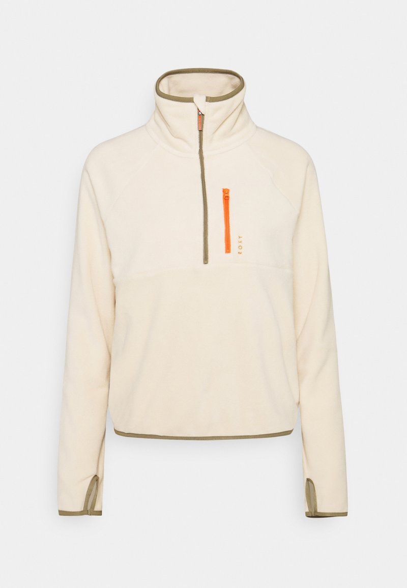 Pull-over en polaire crème avec col haut, bordure olive, poche zippée sur la poitrine orange et passages pour les pouces sur les manches longues.
