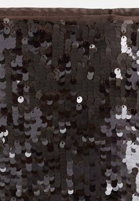 Le tissu en sequins noirs est constitué de sequins circulaires superposés dans des nuances variées de noir et de gris, disposés densément avec une surface brillante et texturée.