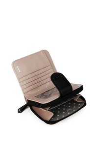 Zipped wallet with a soft pink interior, featuring card slots and a transparent ID section, contrasted by a black exterior and polka dot patterns.