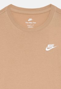 T-shirt à col rond couleur brun clair en tissu doux. Présente un logo Nike blanc brodé sur le devant. Design simple sans motifs.