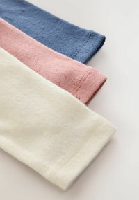 Drei Stoffmuster in Pastellfarben: blassgelb, hellrosa und schieferblau. Strukturierter Strick mit kleinen dekorativen Mustern.