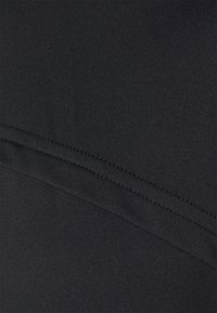 Primer plano de tela negra con una textura suave, que presenta costuras horizontales y diagonales. El material tiene un ligero estiramiento y un acabado mate.