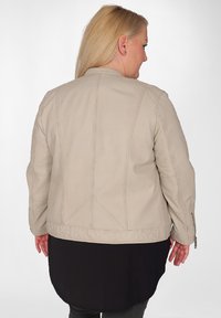Beige faux läderjacka med en strukturerad design. Har en rak skärning, subtila stygn och dragkedjeärmar.