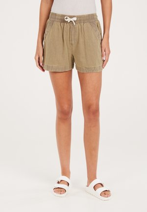 Khaki Shorts mit einem Kordelzug und elastischem Bund, ausgestattet mit Seitentaschen und einem strukturierten Stoff. Kombiniert mit weißen Sandalen.