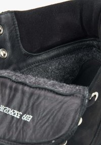 Wnętrze czarnego skórzanego buta z miękką szaro-skalną podszewką, srebrnymi akcesoriami i teksturowanym brzegiem wokół otwarcia.