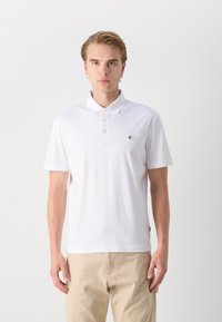 Polo branco de manga curta, feito de tecido suave. Apresenta um colarinho clássico, uma abertura com três botões e um pequeno logótipo no peito.