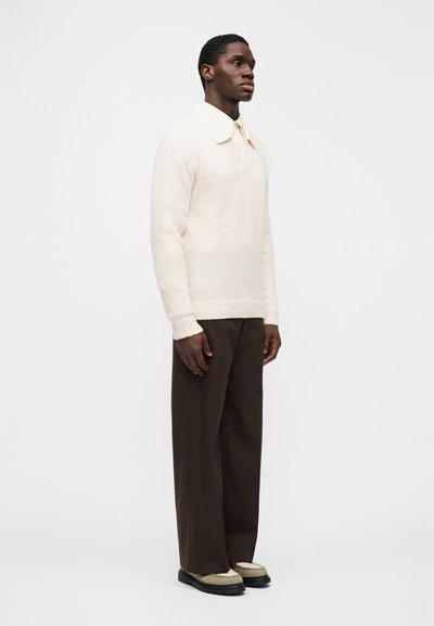 Knit cream sweater with a large collar, paired with brown wide-leg trousers and beige shoes with black soles. Smooth texture and relaxed fit.