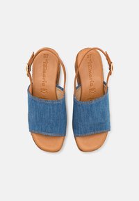 Paire de sandales ouvertes pour femmes avec semelles en cuir couleur tabac et larges brides en denim bleu, équipées d'une bride arrière à la cheville et d'une fermeture à boucle.
