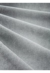 Tela de color gris claro con una textura suave, que presenta capas plegadas que exhiben un sutil patrón de tejido. Apariencia suave y ligera.