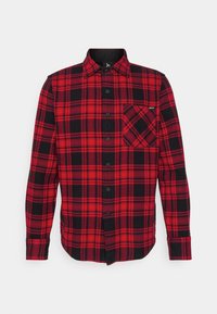 Camisa de franela a cuadros en rojo y negro con cuello, mangas largas, cierre de botones y un bolsillo en el pecho que presenta un patrón diagonal.