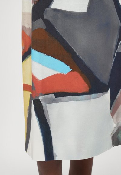 Több színű absztrakt ruha kék, piros, szürke és fehér formák keverékével. Simító anyagból készült, amelynek lágy textúrája van.