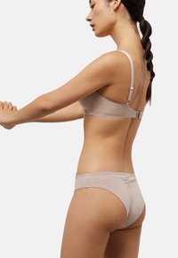 Conjunto de sujetador y bragas a juego de algodón beige, con tirantes ajustables, bordes festoneados y textura suave. Diseño minimalista.