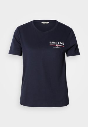 Navy blue cotton t-shirt with a V-neck, short sleeves, featuring white and red logo text "GANT 1949" and design accents on the left chest.