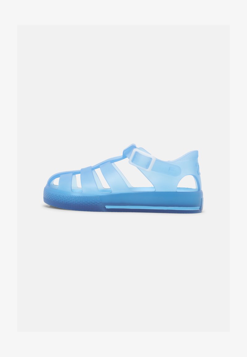 Blue translucent sandals with cut-out straps, ankle strap, and textured blue sole. Lightweight, flexible design for comfort.