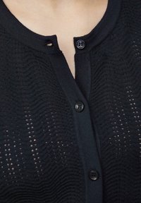 Czarny kardigan dzianinowy z teksturowanym wzorem, z guzikami z przodu i okrągłym dekoltem, wykonany z miękkiego, lekkiego materiału.