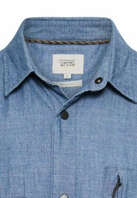 Koszula farbowana na indygo o miękkiej fakturze, z kołnierzykiem w szpic, czarnymi guzikami oraz kieszenią na piersi zapinaną na zamek. Etykieta z napisem "Camel Active", rozmiar L.