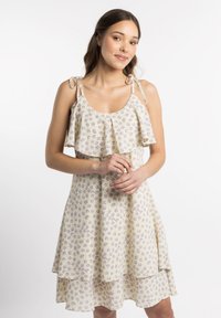 Rochie florală cu un fundal galben și flori violet, având volane stratificate și bretele reglabile, confecționată dintr-un material ușor.