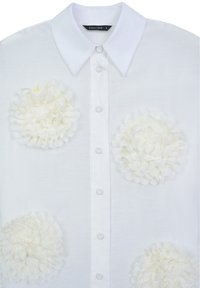 White button-up shirt featuring a classic collar, clear buttons, and large floral appliqués in soft white fabric on the front.