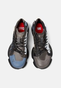 Sneaker mit einer Mischung aus grauem, blauem und weißem Leder sowie schwarzen Gummisohlen, Schnürdesign und kontrastierenden roten Innensohlen, die mit "CAMPER" und "TWINS" beschriftet sind.