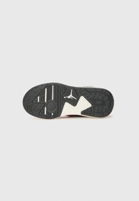Sole di sneaker in bianco e nero con grip testurizzato, motivo distintivo e logo visibile. Presenta scanalature circolari e lineari per la trazione.