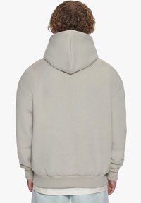 Lys grå hoodie med stor hætte, dropped shoulders, ribbede manchetter og kant, lavet af blødt stof, med en simpel, glat overflade.