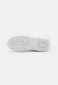 Semelle de sneaker blanche avec du caoutchouc texturé, dotée de motifs rainurés pour une meilleure adhérence et d'une zone de talon légèrement surélevée. Fini lisse et uniforme.