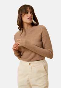 Beige geripptes Sweatshirt mit langen Ärmeln, Rundhalsausschnitt und strukturiertem Stoff. Kombiniert mit cremefarbenen Cordhosen mit Knopfdetail.