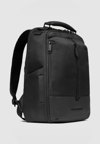 Zaino nero con tessuto strutturato, numerosi compartimenti con cerniera, spallacci imbottiti e manico superiore per il trasporto.