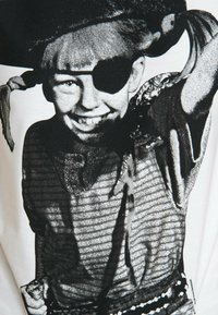 White T-shirt with a black-and-white graphic of a child dressed as a pirate, featuring an eye patch, striped shirt, and decorative accents.