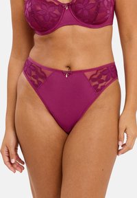Sous-vêtements en dentelle et en mesh mauve avec des motifs floraux sur les côtés, un arrière lisse et un petit nœud décoratif à l'avant.