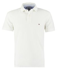 Polo blanc à manches courtes avec deux boutons, col avec doublure intérieure bleue et petit logo Tommy Hilfiger sur la poitrine gauche.