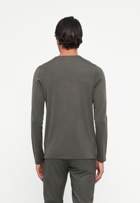 Long-sleeve shirt in dark grey, made of soft knit fabric. Features a round neck and fitted design with ribbed texture.