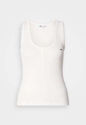 Camiseta sin mangas blanca con cuello redondo, que presenta tres botones en la parte delantera y un pequeño emblema de logo en el área izquierda del pecho.