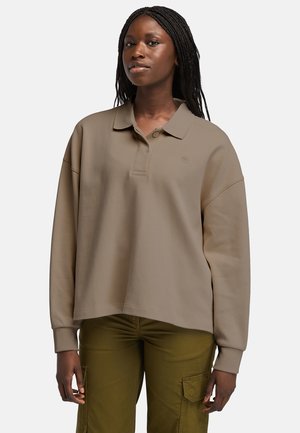 Khaki oversized polo shirt with a ribbed collar and cuffs, featuring a three-button placket and a subtle logo on the chest.