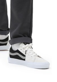Sneakers bianchi e neri con tomaia in tela, colletto imbottito, chiusura con lacci, dettagli grigi e suola in gomma bianca.