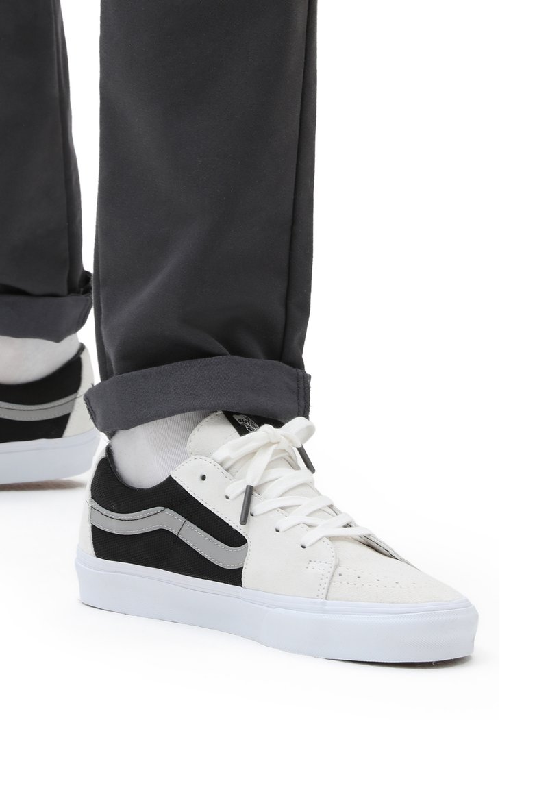 Sneakers bianchi e neri con tomaia in tela, colletto imbottito, chiusura con lacci, dettagli grigi e suola in gomma bianca.