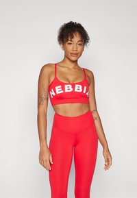 Sujetador deportivo rojo con texto blanco "NEBBIA" y tirantes finos, combinado con leggings rojos de cintura alta; textura suave, diseño ajustado.